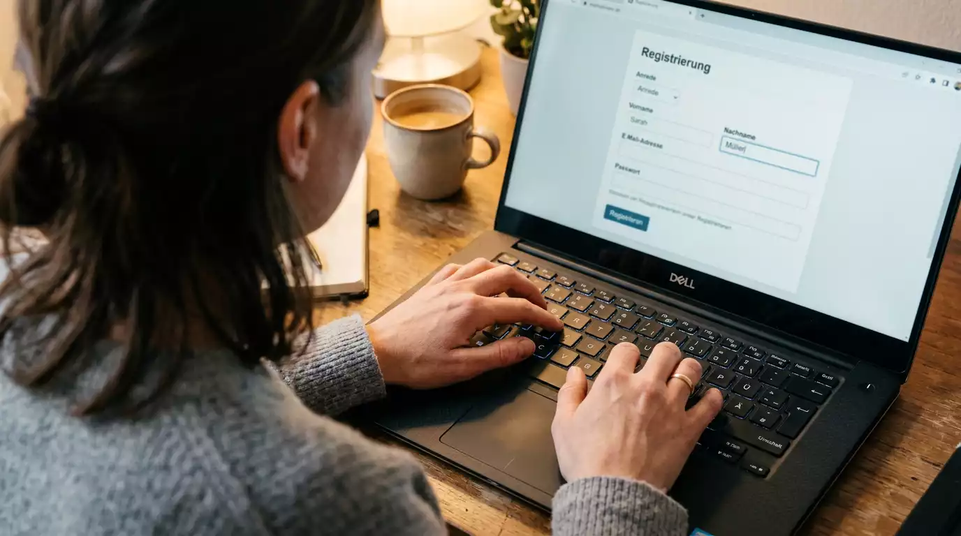 Hände tippen die Anmeldedaten in ein Formular auf dem Laptop