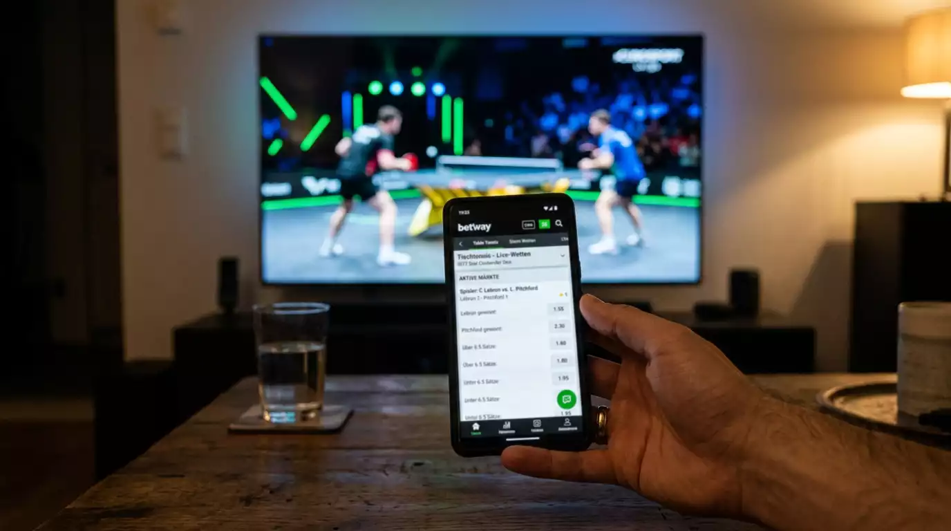 Smartphone zeigt eine Wettoberfläche während ein WTT-Spiel im Hintergrund läuft